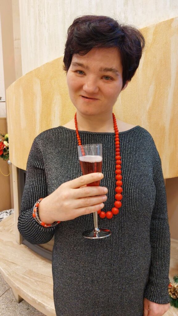 Uśmiechnięta mieszkanka stojąc pozuje do zdjęcia z szampanem w dłoni