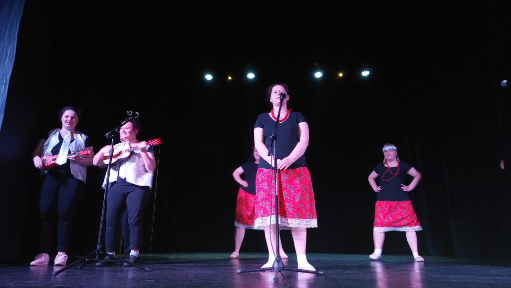 Zespół Michalinki na scenie podczas swojego występu. Mieszkanki grają na instrumentach, śpiewają i tańczą. 