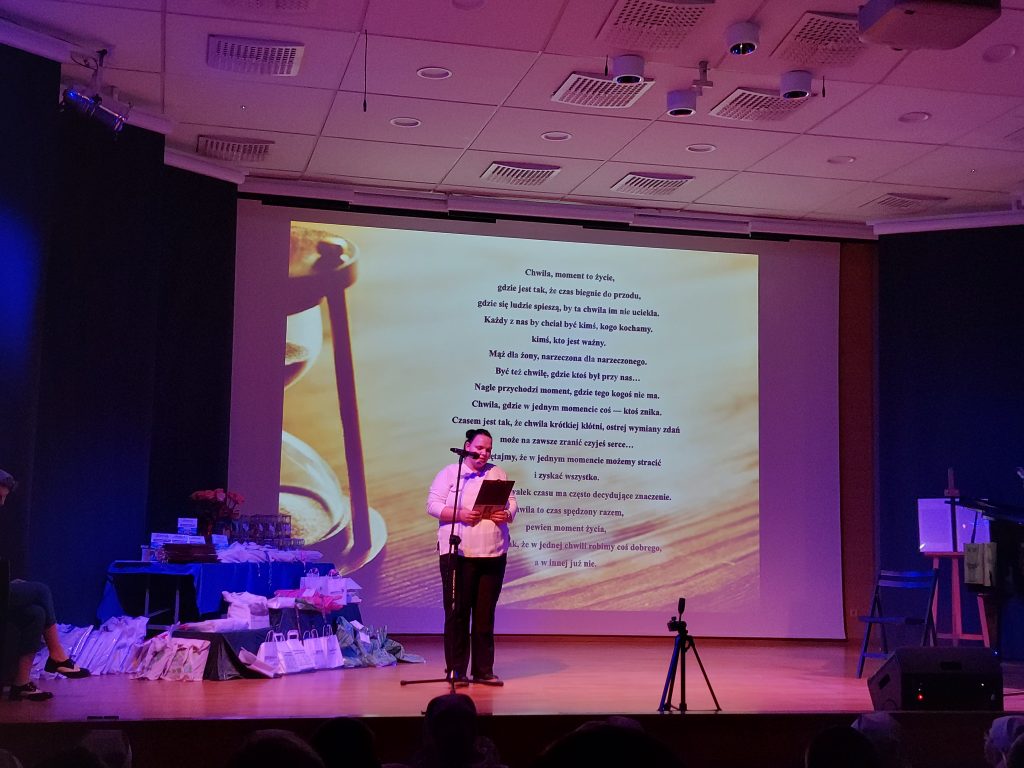 Laureatka konkursu czytająca wiersz, w tle na prezentacji wyświetlony tekst wiersza. 