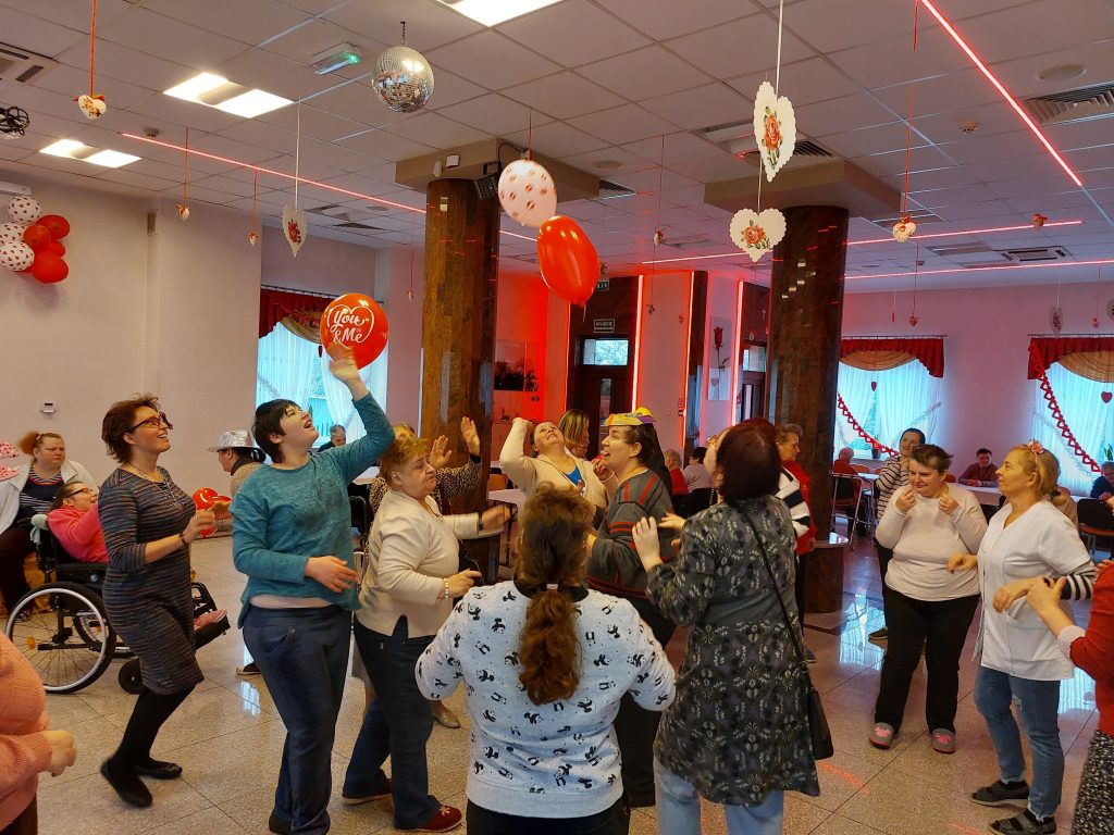 Zabawa taneczna na sali integracyjno - terapeutycznej. Terapeuci razem z mieszkankami odbijają balony tańcząc