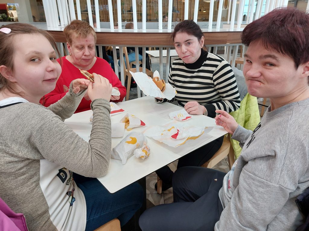 Cztery mieszkanki siedzą przy stole i pozują do zdjecia podczas jedzenia w Mc Donald's