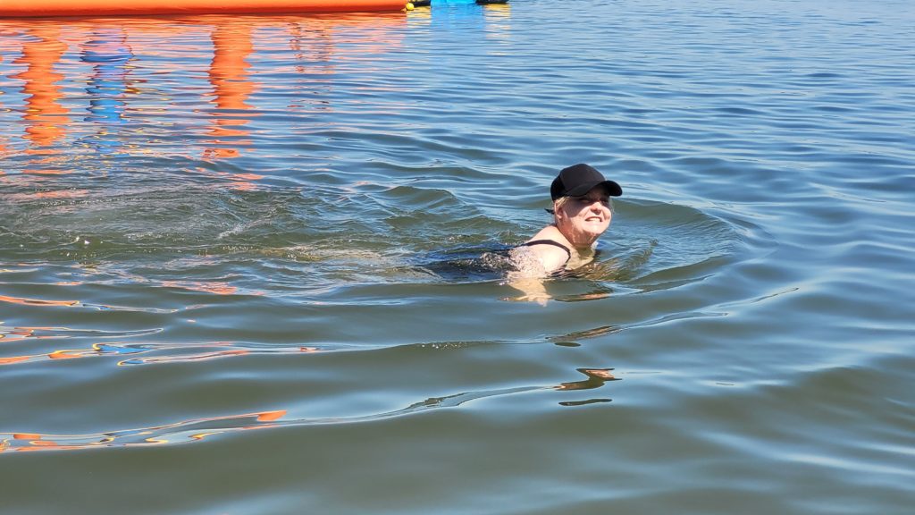 Uśmiechnięta mieszkanka pozuje do zdjęcia podczas pływania w wodzie 